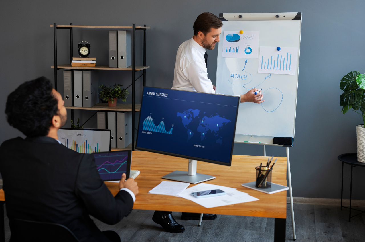 Two businessmen in an office presentation, discussing charts and data, representing professional training like a 100% Job Guarantee Course.